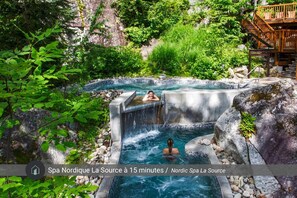 Ein Thermalbadbereich mit einer Holzterrasse und einem Wasserfall.