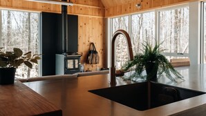 Una cocina moderna con paredes de madera, un ventanal grande y un lavamanos.