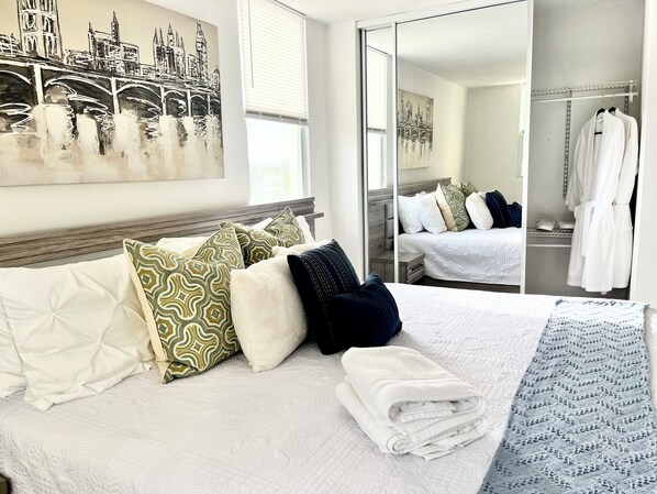 Une chambre d’hôtel avec un grand lit, un miroir et un tableau représentant un paysage urbain.