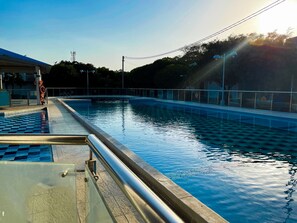 A swimming pool with a tiled deck and a metal railing.