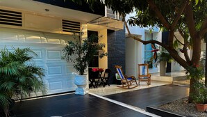 Ein modernes Haus mit Garage, einer gefliesten Terrasse, zwei Schaukelstühlen und Topfpflanzen.