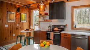 Eine moderne Küche mit Holzwänden, einer zentralen Kochinsel und Pendelleuchten.