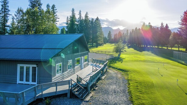 Un chalet doté d’une terrasse et offrant une vue sur un terrain de golf.