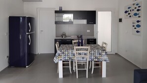 Una cocina compacta con refrigerador, una mesa de comedor con sillas y un ventanal sobre la encimera.