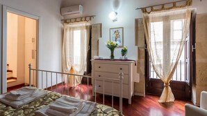 Ein Schlafzimmer mit einem Bett, einem Schminktisch, einem Spiegel und einem Fenster mit Vorhängen.