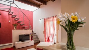 Ein modernes Wohnzimmer mit Fernseher, einer Treppe und einem Blumenstrauß.