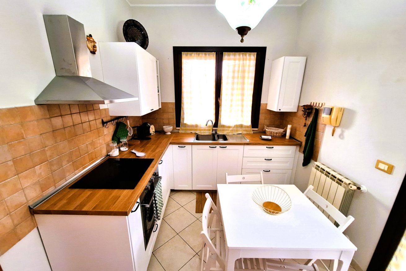 A compact kitchen with a stove, sink, and white cabinets.