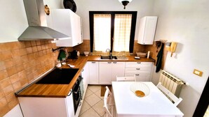 Una cocina compacta con estufa, pileta y alacenas blancas.