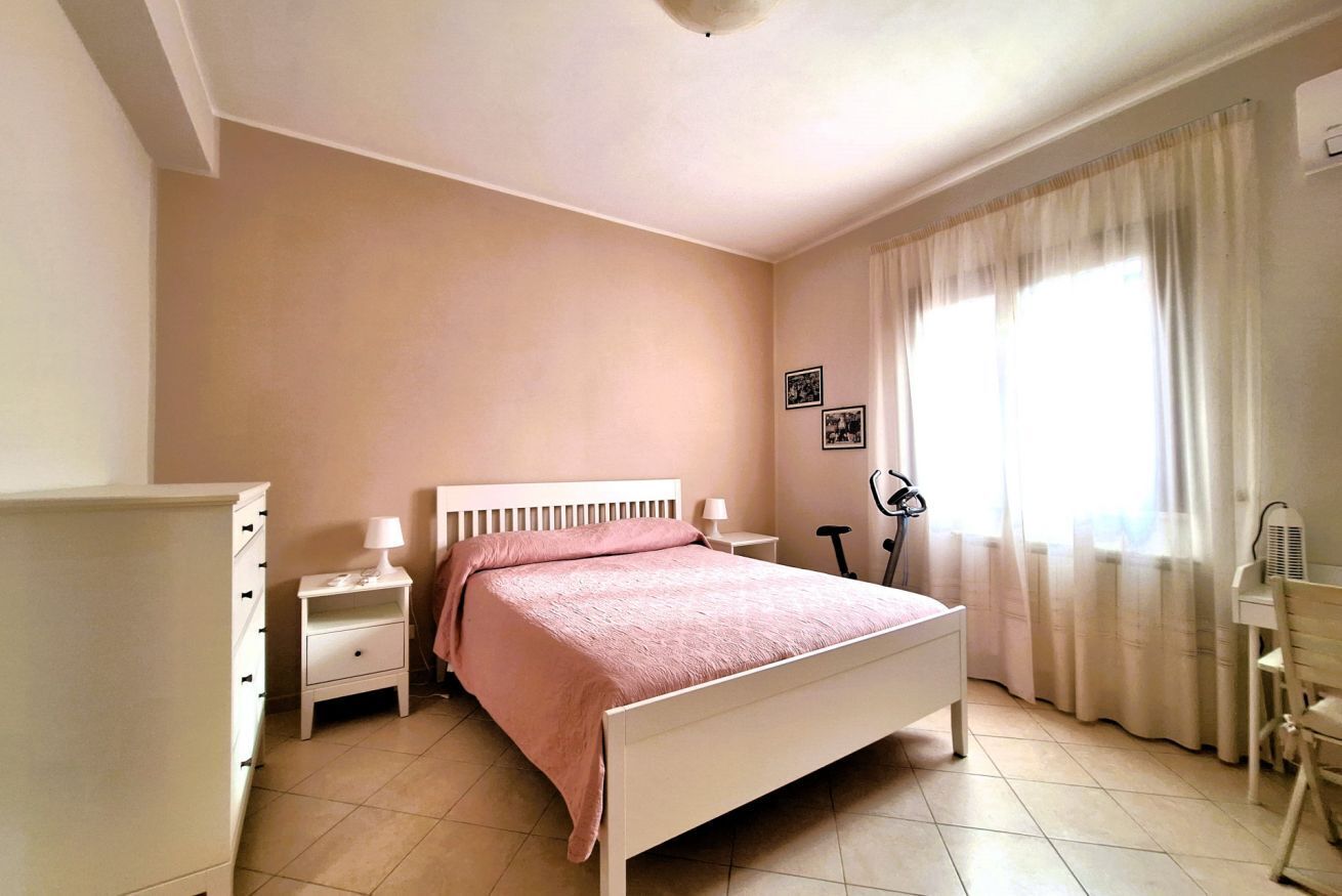 A bedroom with a bed, a nightstand, a dresser, a chair, and a window with curtains.
