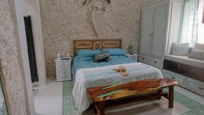 Quarto com cama, um banco de madeira, guarda-roupa e um objeto decorativo na parede.