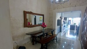 Uma sala espaçosa com um banco de madeira, um espelho grande e um tapete estampado.