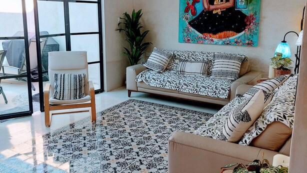 Uma sala de estar moderna com um sofá, poltrona e uma pintura grande na parede.