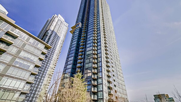A high-rise building with a modern glass facade, multiple balconies, and a clear sky. - Cozy Condo near CN Tower - downtown (Toronto)
