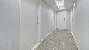 Un couloir étroit aux murs blancs et au sol orné d’un motif en chevrons.