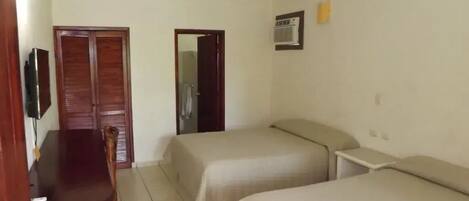 A room with two beds, a wooden desk, and a TV.