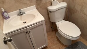 Un baño con lavamanos blanco, inodoro y zona de ducha.