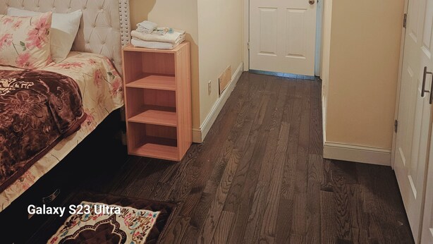 Un dormitorio con una cama, un estante de madera, una puerta y un pasillo.