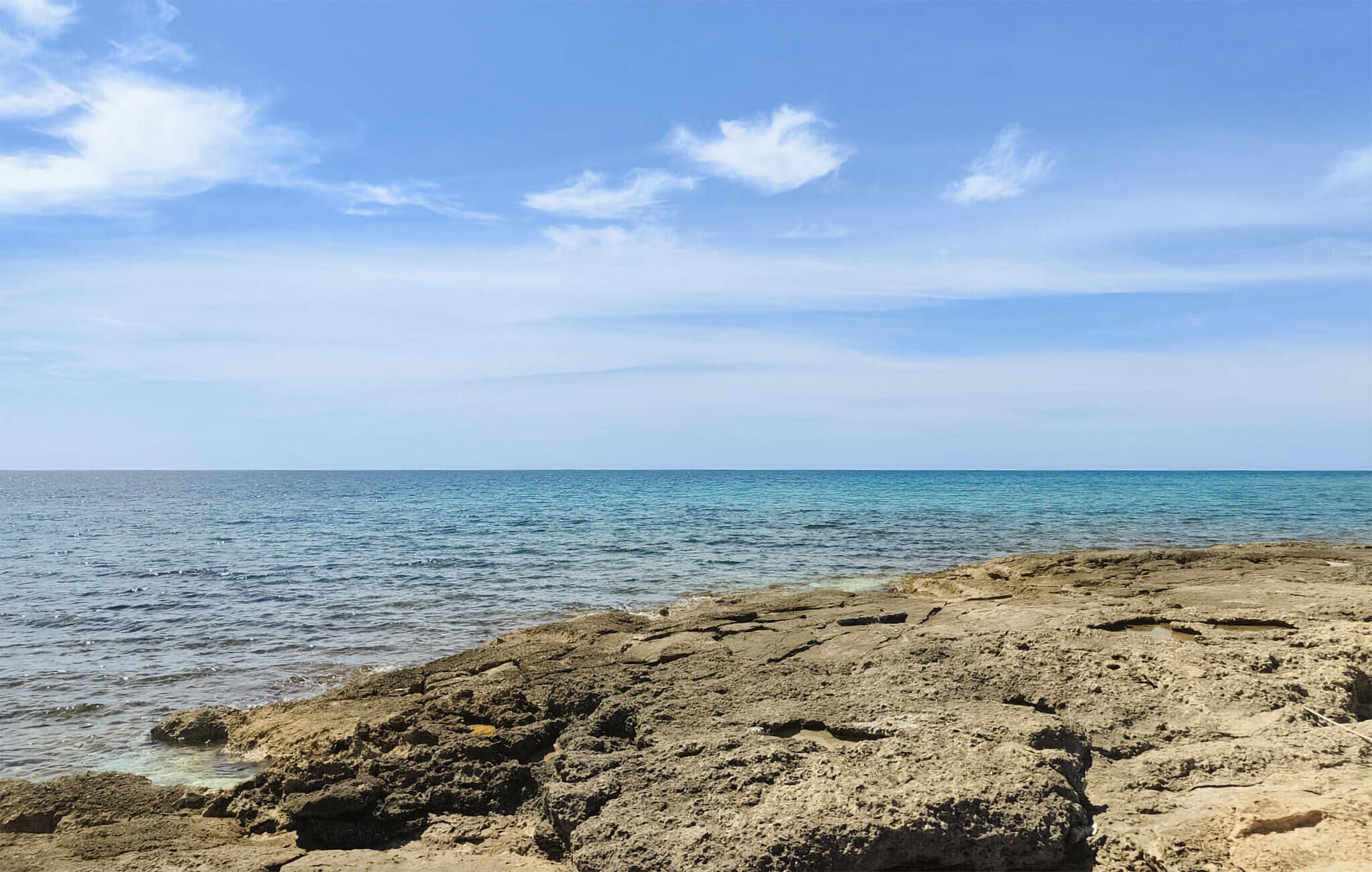 A rocky shoreline with clear blue sea and sky.