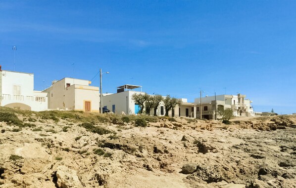 A coastal building complex with multiple structures, some with flat roofs and others with sloped roofs, situated on a sandy terrain with sparse vegetation. - 1 bedroom gorgeous home in Taviano (Taviano)