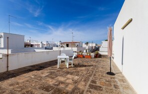 A rooftop patio with a table and chairs, potted plants, and a clear blue sky. - 1 bedroom gorgeous home in Taviano (Taviano)