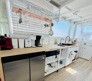 A modern kitchen with a dishwasher, coffee maker, and kettle.