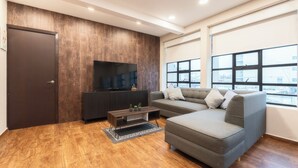 A modern living room with a sectional sofa, a flat-screen TV, a dark wooden cabinet, and large windows. - ZIELO Rentals 5 de Febrero (Mexico City)