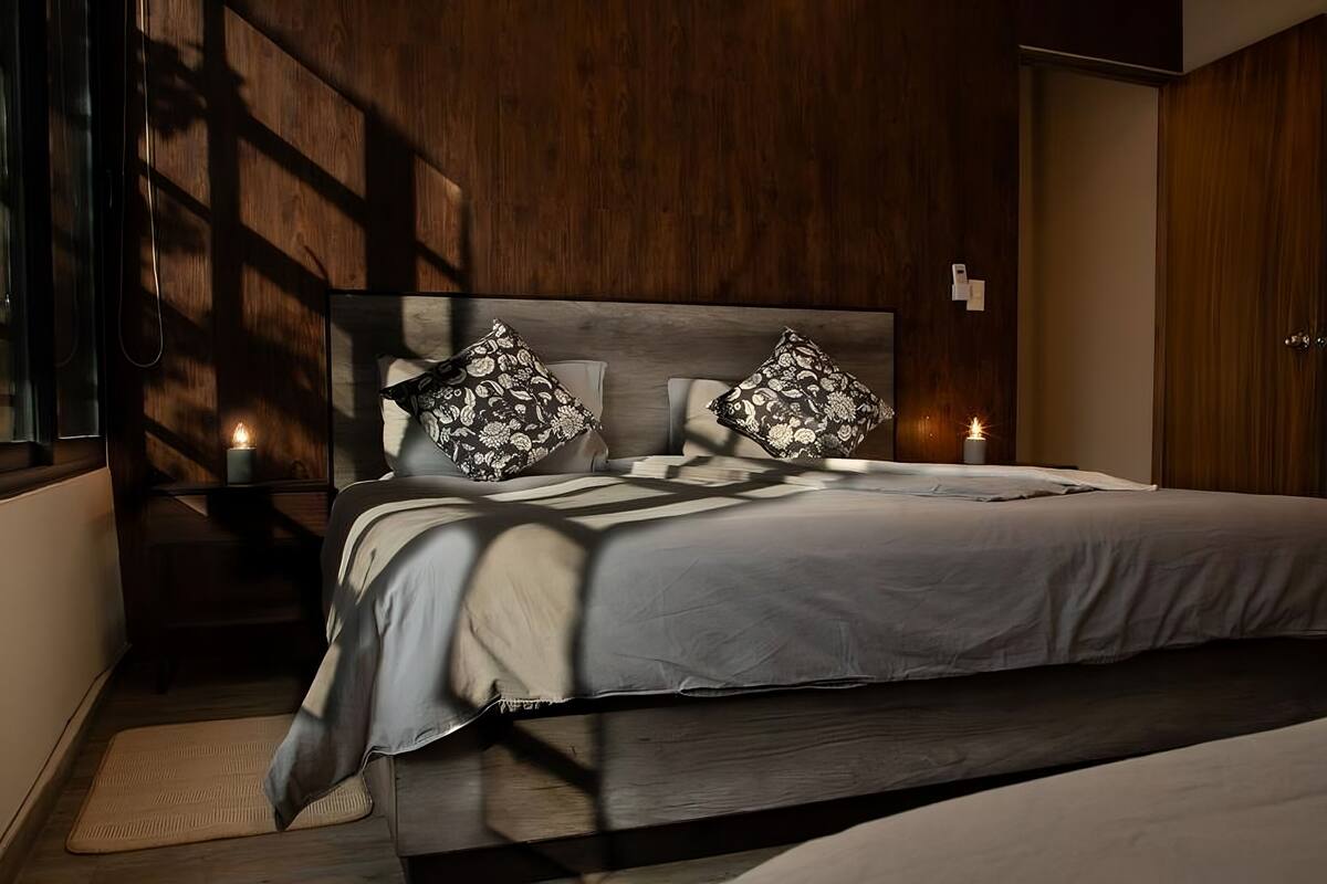 A bedroom with a large bed, two bedside tables with candles, and a wooden headboard.