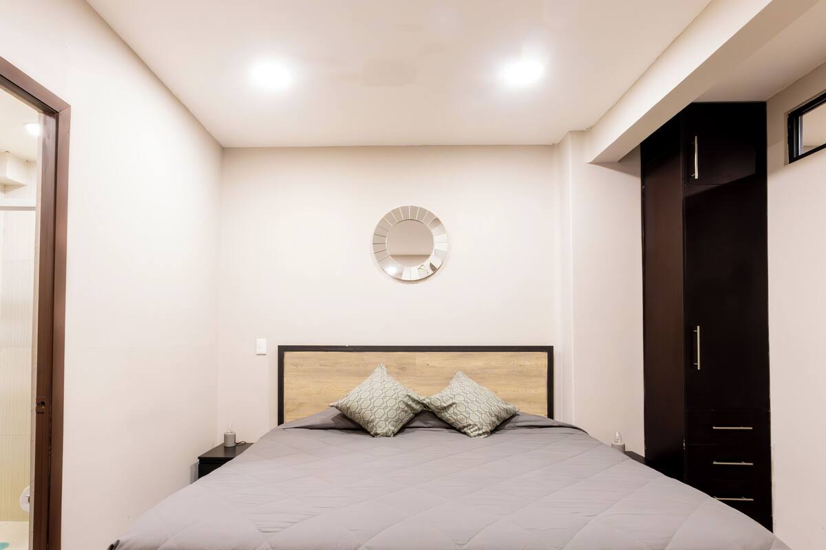 A bedroom with a bed, a round mirror, and a wardrobe.