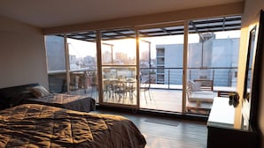A bedroom with a large bed, a desk, and a balcony with a table and chairs. - ZIELO Rentals 5 de Febrero (Mexico City)