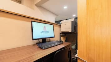 Una habitación de negocios con un monitor de computadora mostrando 'CDMX Rentals', un teclado y una impresora sobre un escritorio de madera.