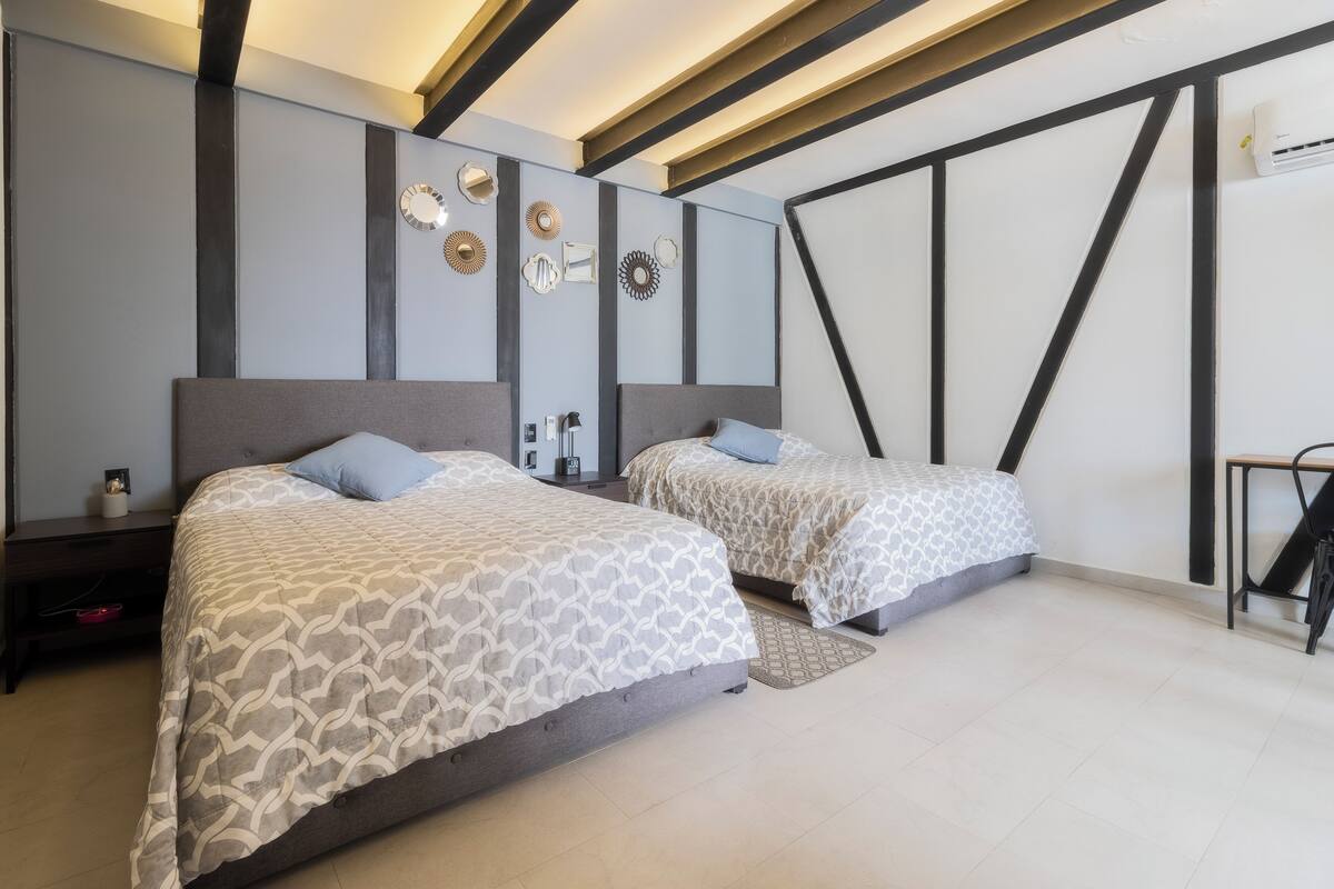 A modern bedroom with two beds, a wall clock, and decorative wall art.