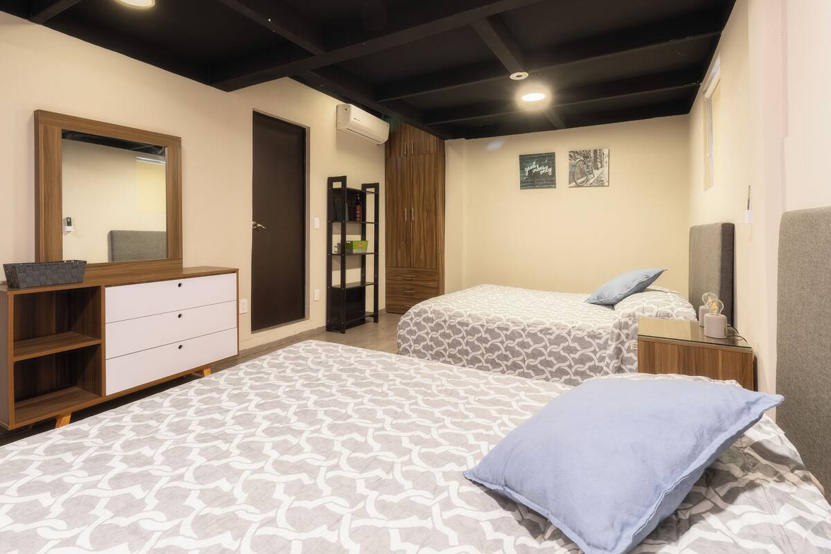 A bedroom with two beds, a dresser, a mirror, and a wardrobe.