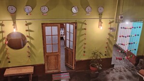 Ein Flur mit Uhren an der Wand, einer Holztür und einem Blumentopf.