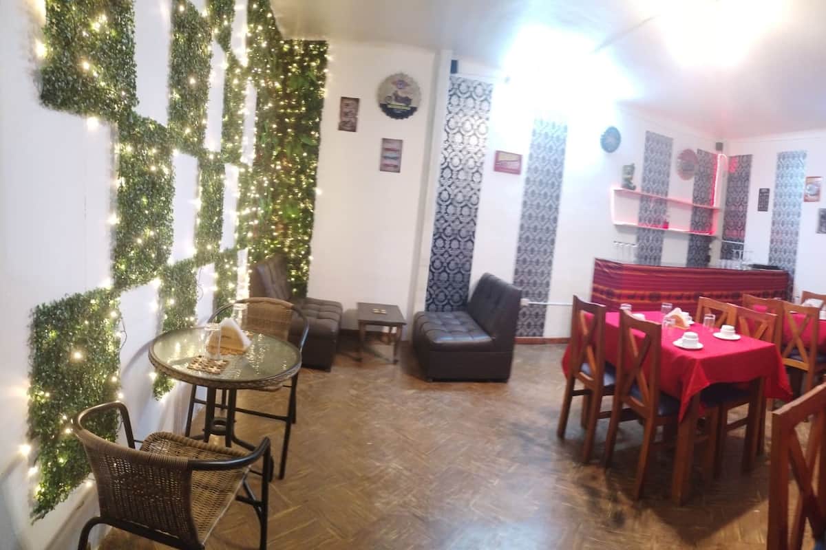 A dining area with a red tablecloth, wooden chairs, and a television mounted on the wall.