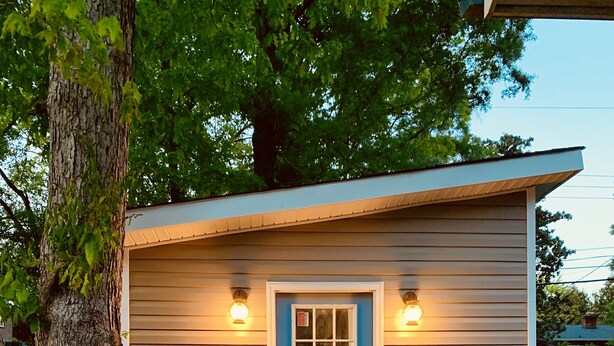 A small, single-story building with a blue door and two wall-mounted lights.