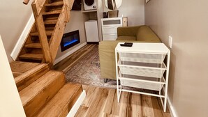 A cozy room with a wooden staircase, a white sofa, a small white table, and a white cabinet.