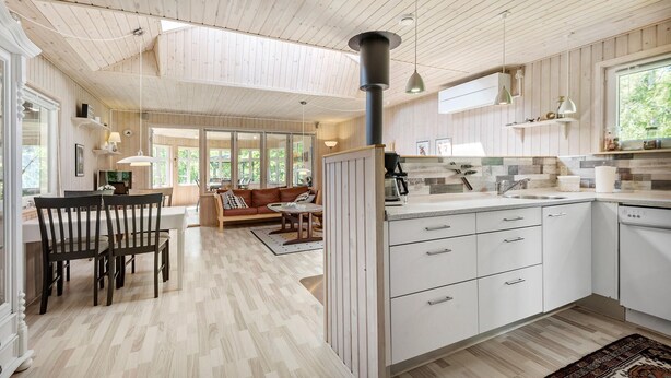 A spacious kitchen with white cabinets, a central island, and a dining area with a wooden table and chairs.