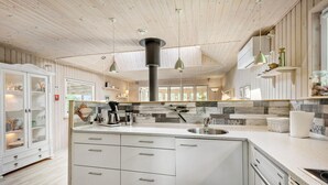 A modern kitchen with white cabinetry, a central island, and a stone backsplash.