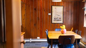 Comedor con paneles de madera, una mesa, sillas y una obra de arte enmarcada en la pared.