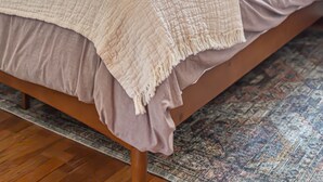 Un dormitorio con cama, almohadas, mesita de noche y ventana.