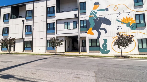 A multi-story building with a modern facade, large windows, and a mural on the side. - Conway Professionally Managed Buyout in DT Nash (Nashville)