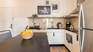 A modern kitchen with a black countertop, stainless steel appliances, and a basket of lemons. - Conway Professionally Managed Buyout in DT Nash (Nashville)