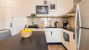 A modern kitchen with a black countertop, stainless steel appliances, and a basket of lemons. - Conway Professionally Managed Buyout in DT Nash (Nashville)