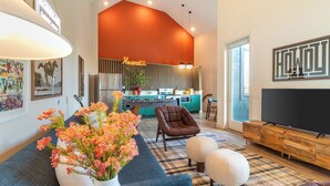 A modern living room with a sofa, ottoman, and a flat-screen TV. - Conway Professionally Managed Buyout in DT Nash (Nashville)
