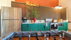 A kitchen with a foosball table, a refrigerator, a coffee maker, and a stove. - Conway Professionally Managed Buyout in DT Nash (Nashville)