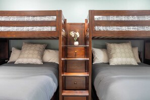 Ein Zimmer mit zwei Etagenbetten, jeweils mit einem Kissen und einer kleinen Holztrennwand mit einer Vase.