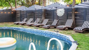 A backyard with a swimming pool, lounge chairs, and a clock on a wall. - Red River by Avantstay Shared Pool + Hot Tub 20 Minutes to Downtown Austin (Austin)