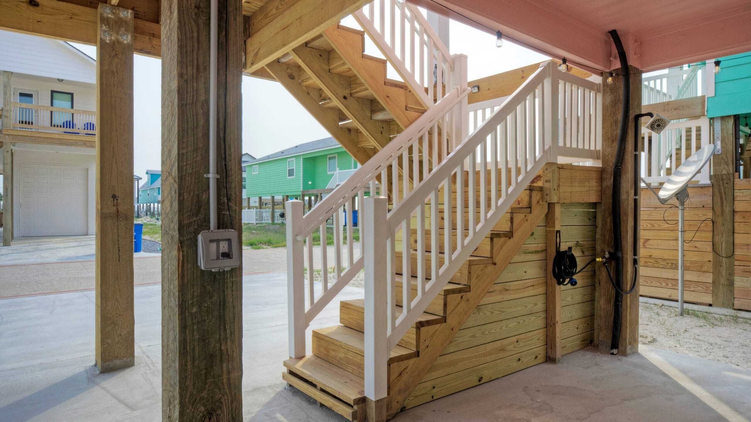 Una escalera de madera con barandillas blancas que lleva a un acceso cubierto.