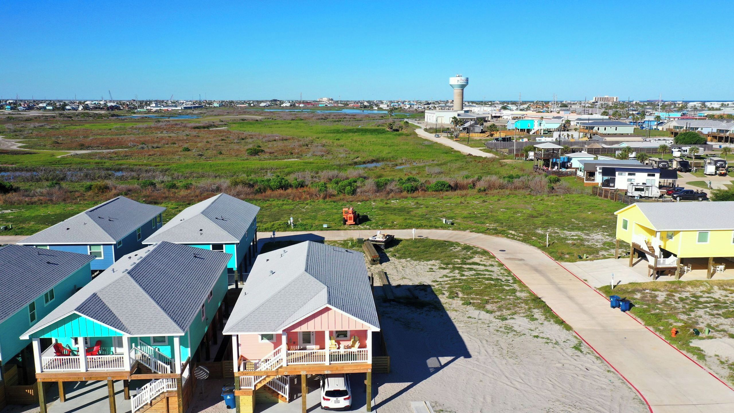 Une zone côtière avec des maisons de plage, un château d’eau et une route asphaltée.