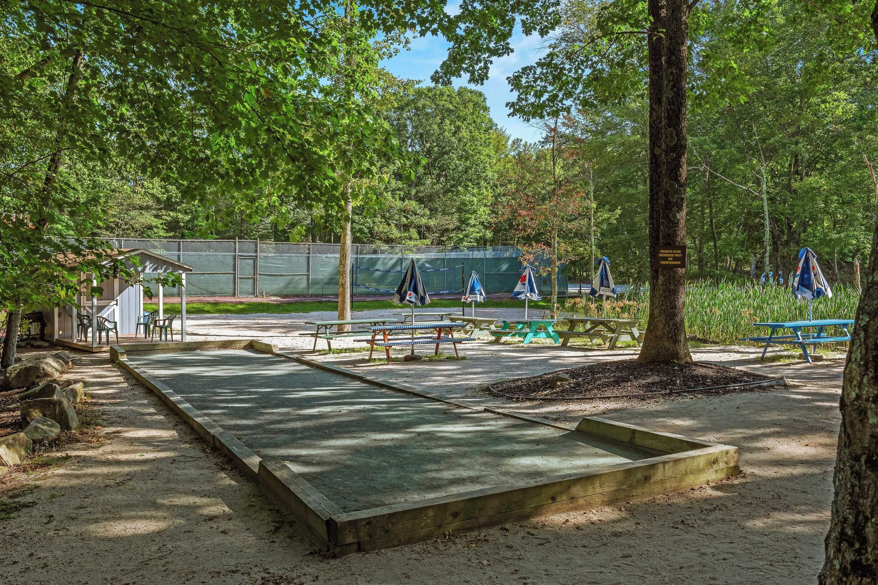 A park with picnic tables, a playground, and a fenced area.